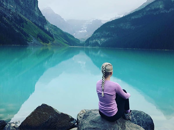 woman sitting at the edge of a lake