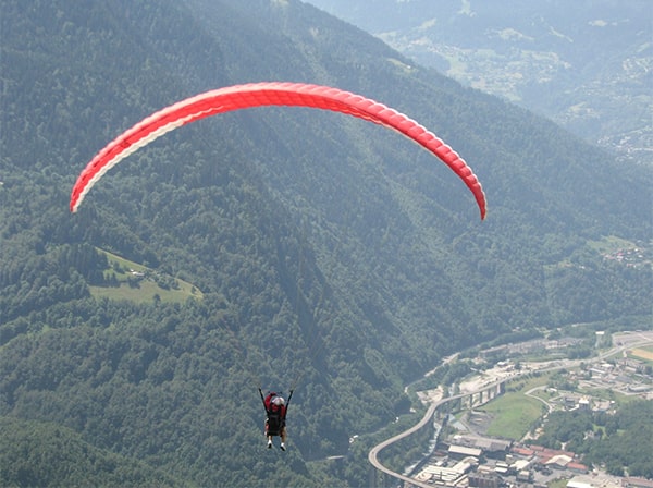 a paraglider high above a valley